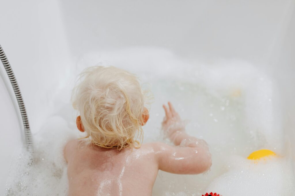 A kid enjoying the soap bubbles while bathing