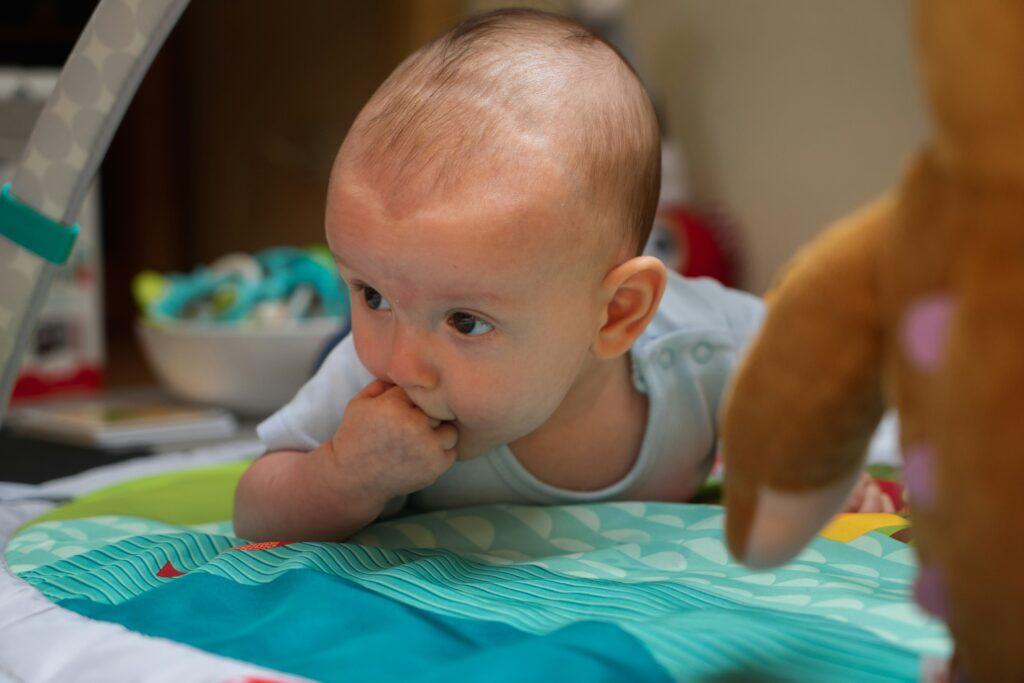 baby in blue tank top on non-toxic play mat