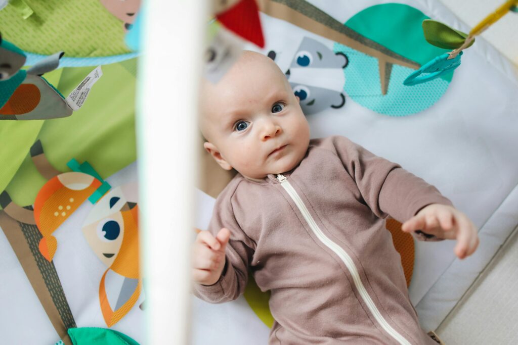 Baby in pink zip up onesie lying on themed non-toxic baby play mats
