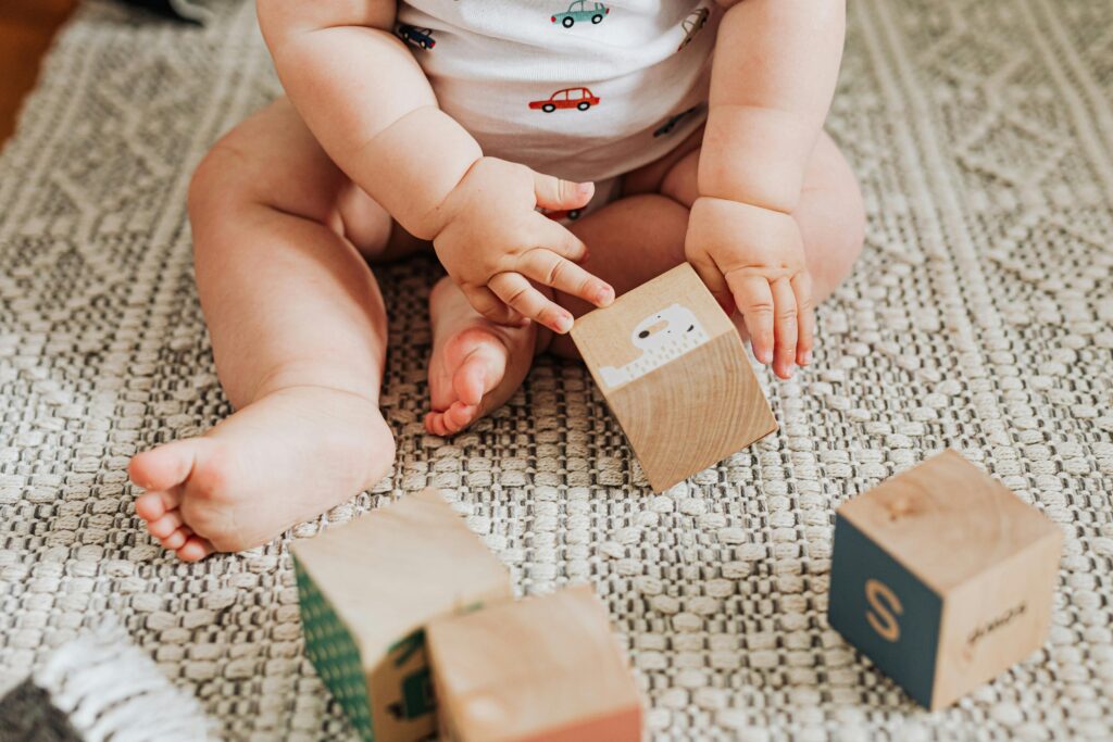 Baby sitting on non-toxic baby play mats playing with wooden toy blocks