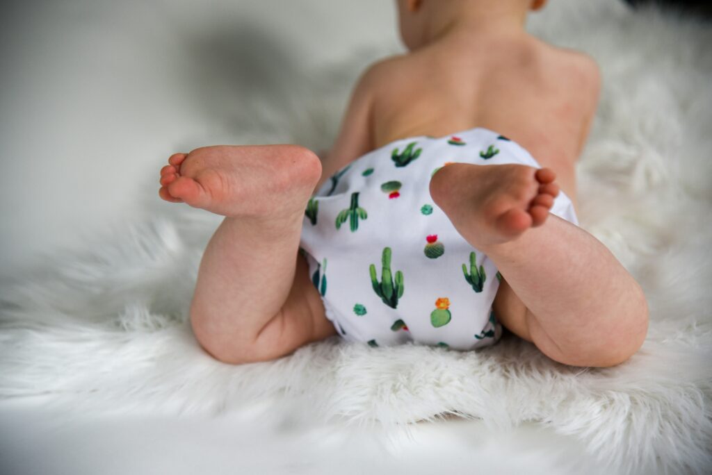 A baby wearing a non-toxic cloth diaper lies on a faux sheepskin