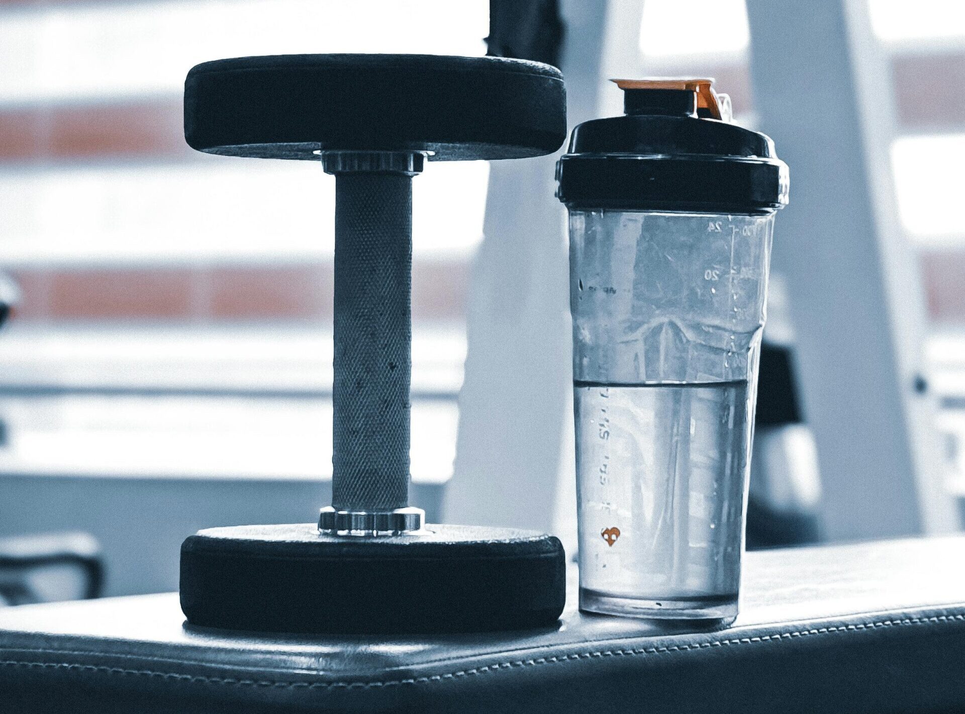 Dumbbell and plastic-free water bottle on gym bench