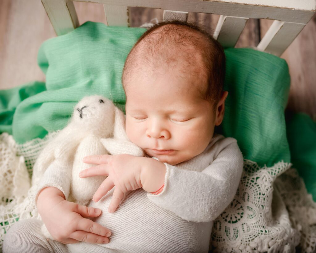 Newborn sleeping with rabbit toy in a non-toxic bassinet