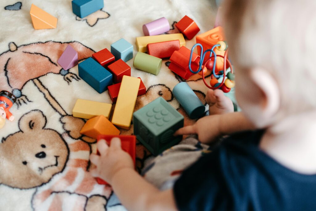 Toddler playing toy blocks on non-toxic baby play mats