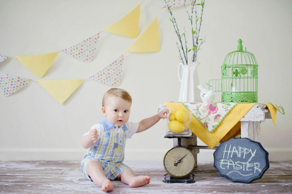 Charming baby wearing an organic easter outfit enjoying a playful Easter scene with decorations inside.