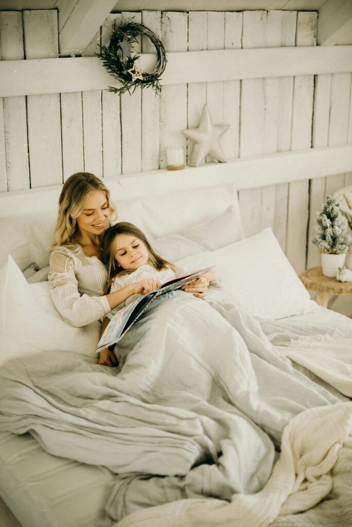 A mother and daughter enjoy a relaxing moment reading a book in a beautifully decorated bedroom.