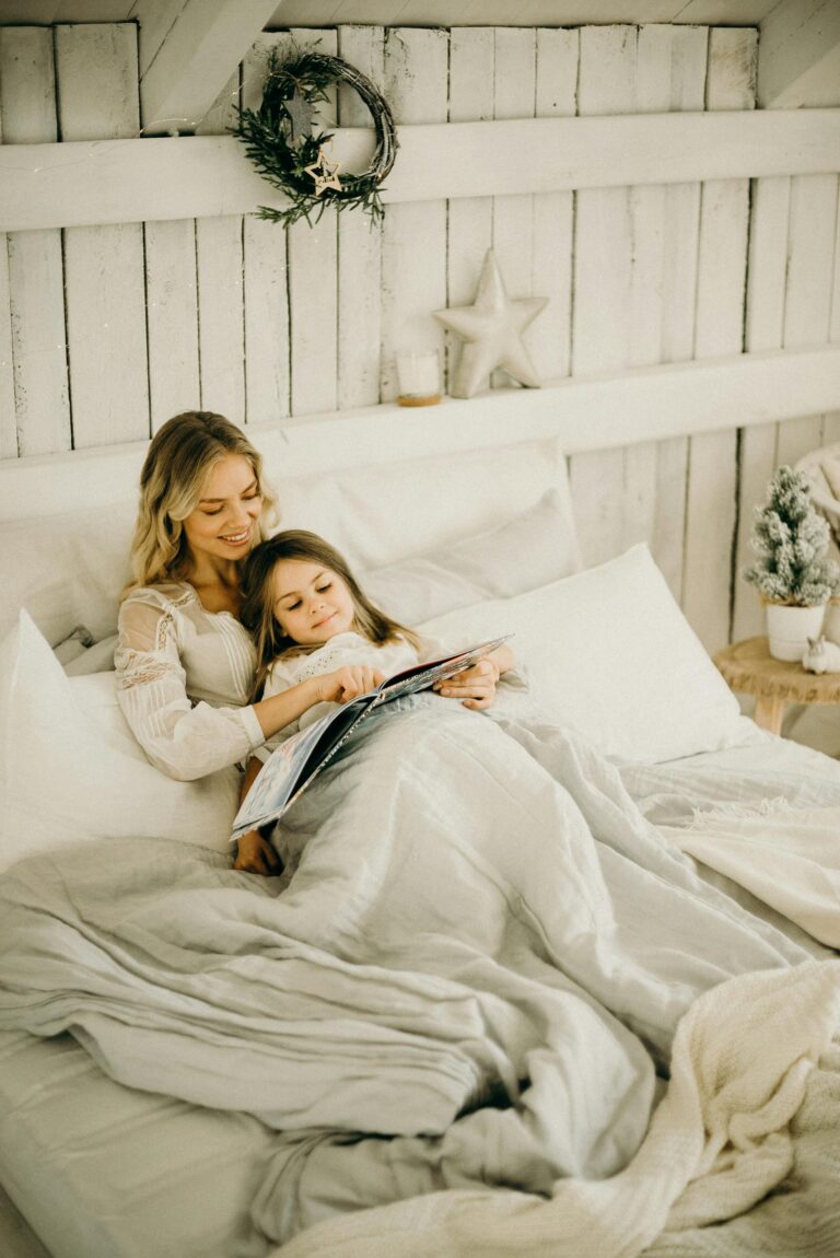 A mother and daughter enjoy a relaxing moment reading a book in a beautifully decorated bedroom.