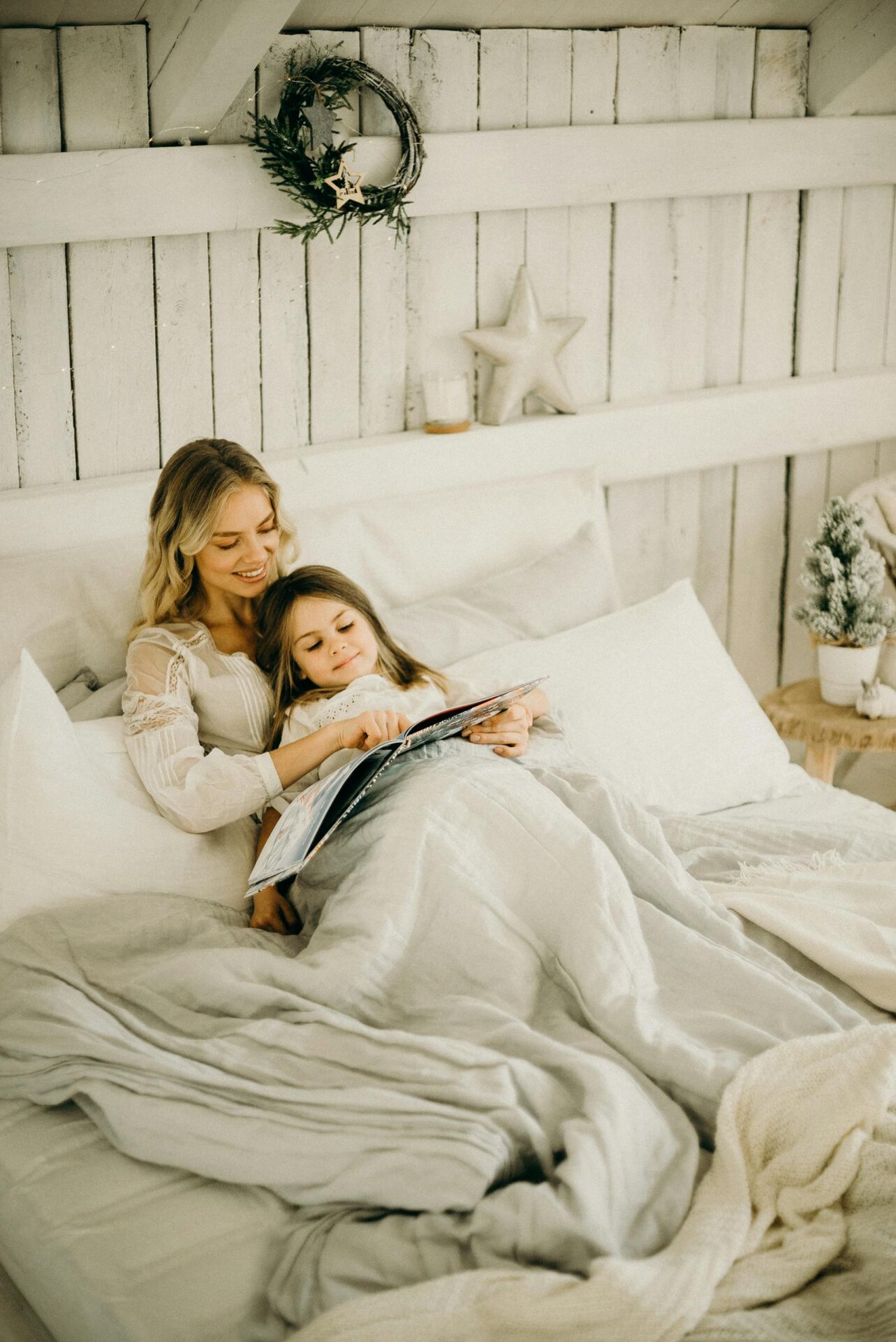 A mother and daughter enjoy a relaxing moment reading a book in a beautifully decorated bedroom.