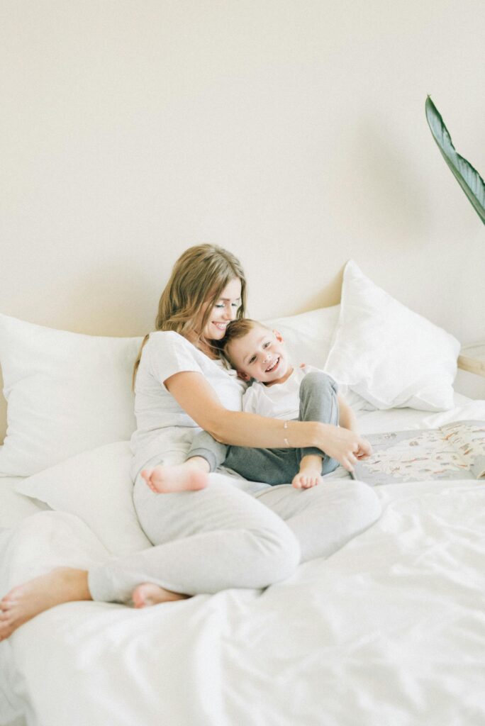 Happy mother and son enjoying quality time cuddling on a non-toxic mattress at home.