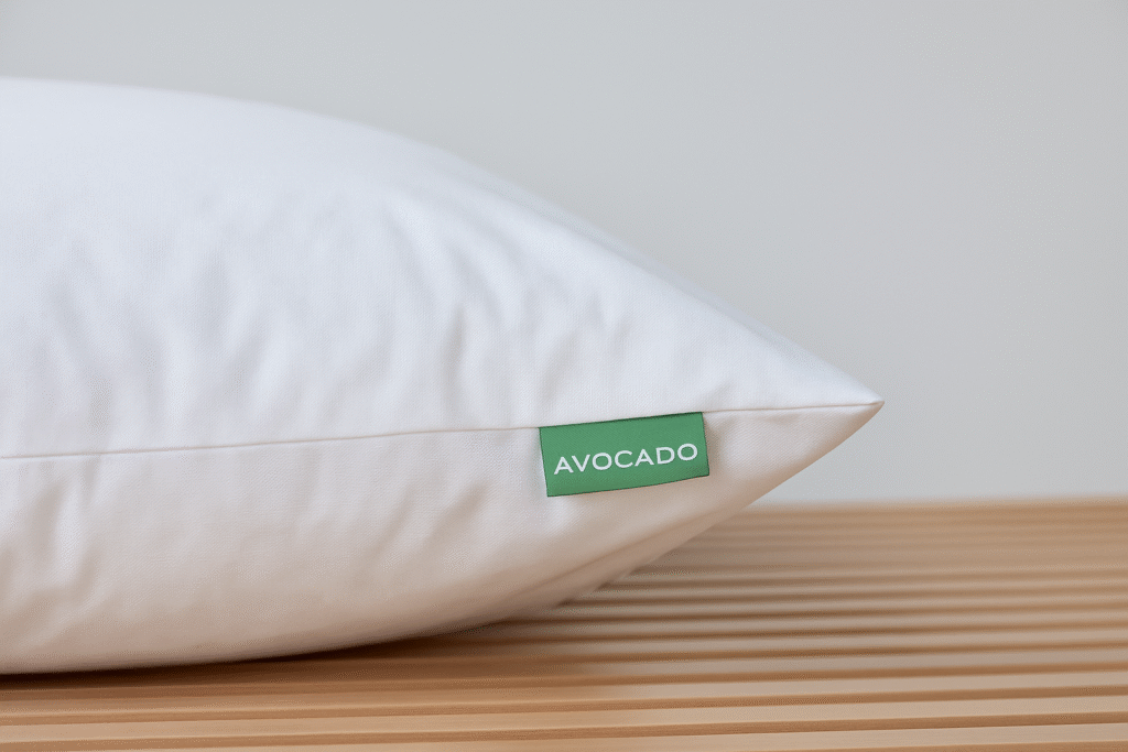 Close-up of a white organic cotton pillow with green Avocado tag on a wooden slatted bench