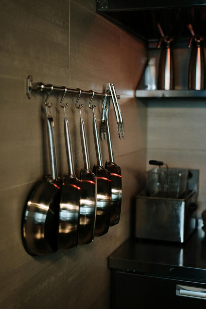 Elegant arrangement of non-toxic cookwaree hanging in a contemporary kitchen setting.