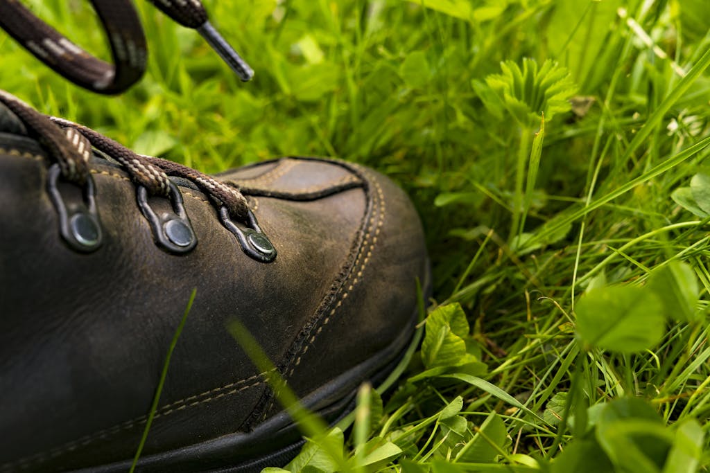 Leather hiking shoe close-up on vibrant green grass, perfect for outdoor exploration concepts.