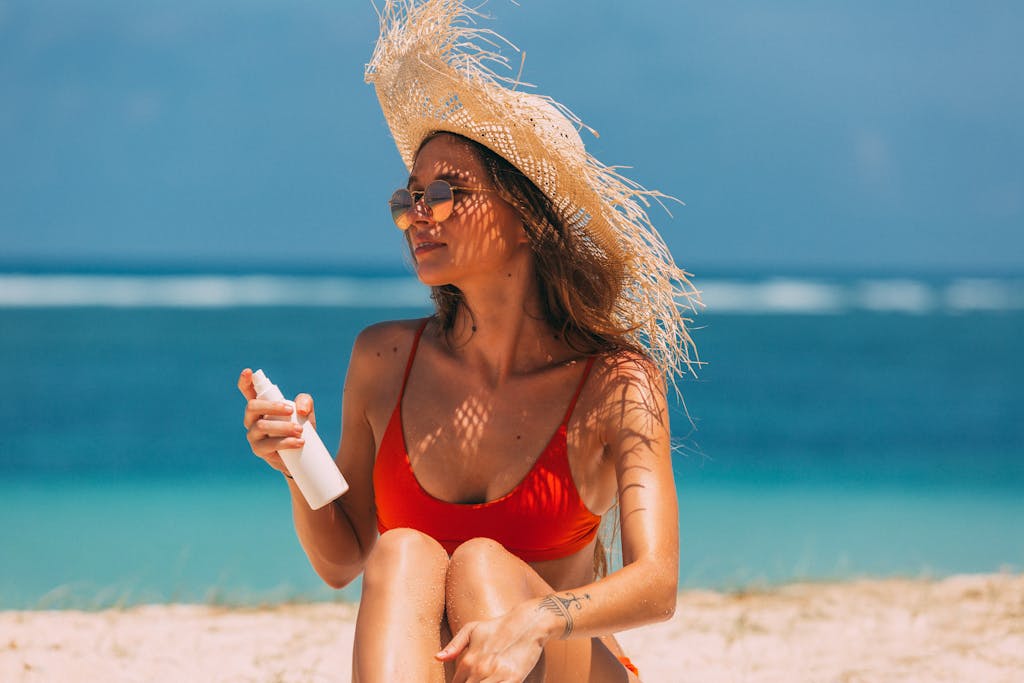 Stylish woman with straw hat and non-toxic sunscreen relaxes on a sunny beach.