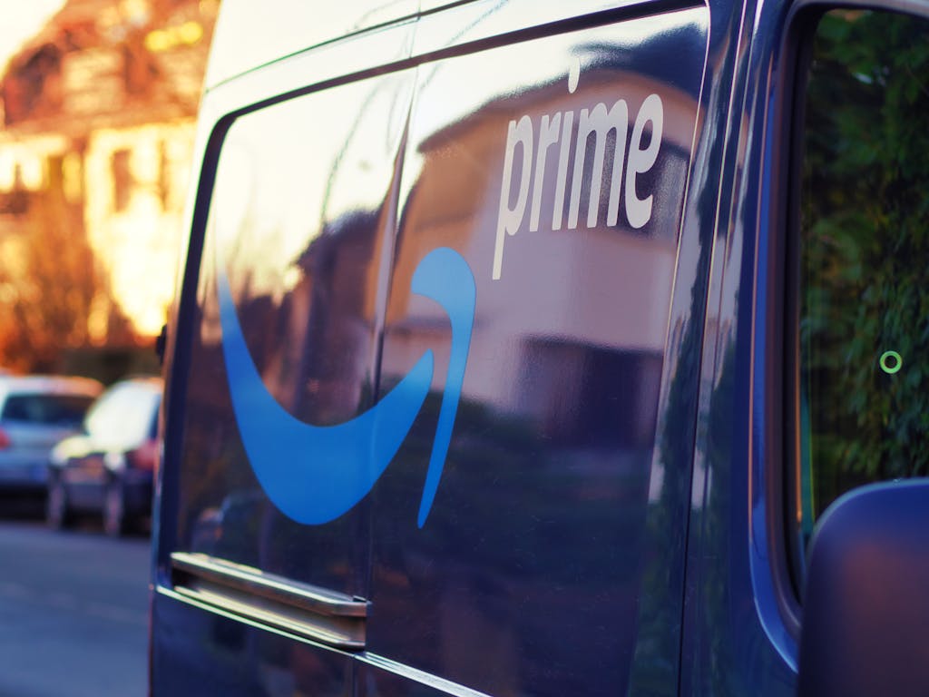 A close-up shot of an Amazon Prime delivery van featuring a prominent blue logo and text 'prime'.