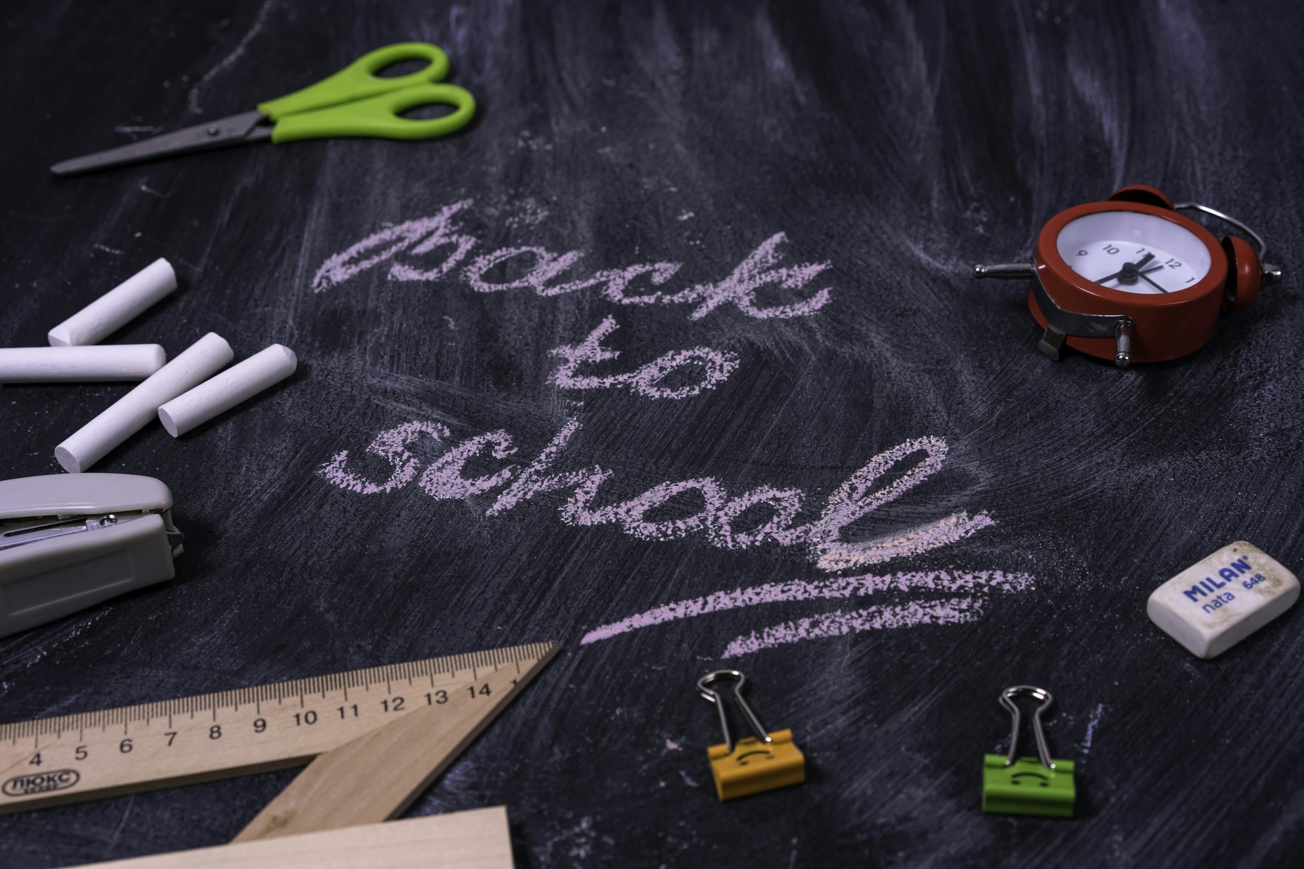 An arrangement of non-toxic school supplies with 'back to school' written on a chalkboard.