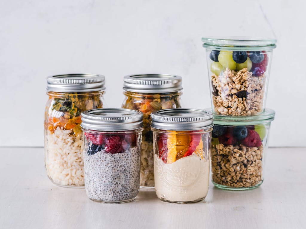 Close-up of healthy food jars containing granola, fruits, and yogurt, portraying non-toxic living for beginners.