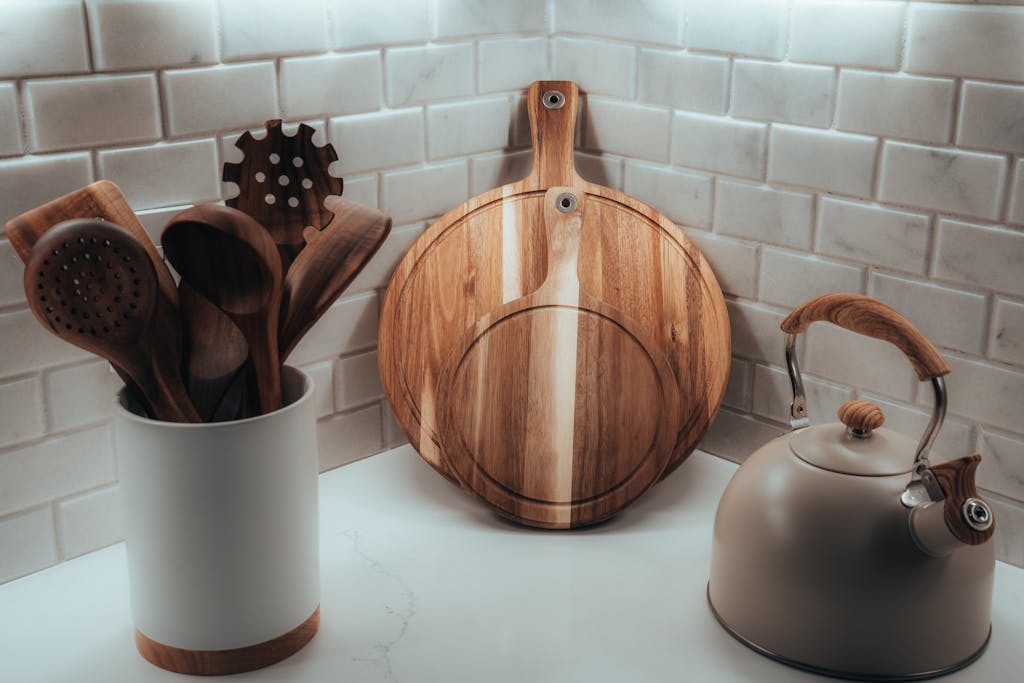 Cozy kitchen corner with wooden utensils, cutting board, and tea kettle against a tiled wall display non-toxic living for beginners.