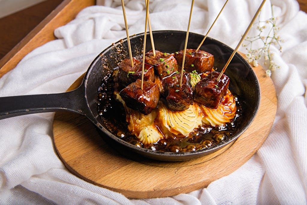 Delicious grilled skewers with sauce served on a rustic wooden platter, perfect for a gourmet meal.