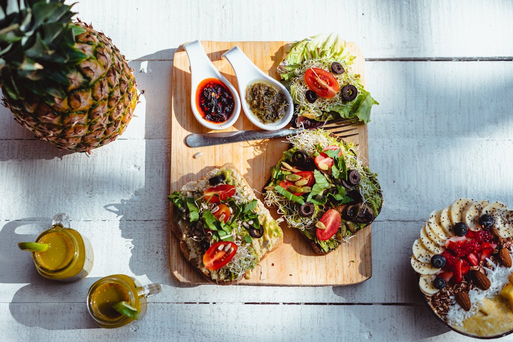 Top view of a vibrant and healthy brunch spread with sandwiches, fruits, and juices on a non-toxic wood cutting board.