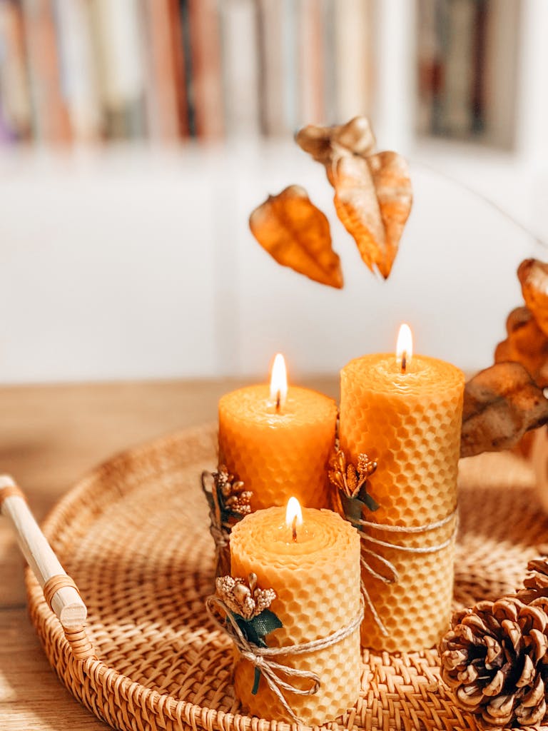 Warm autumn scene with handmade beeswax candles on a wicker tray, evoking a cozy atmosphere.