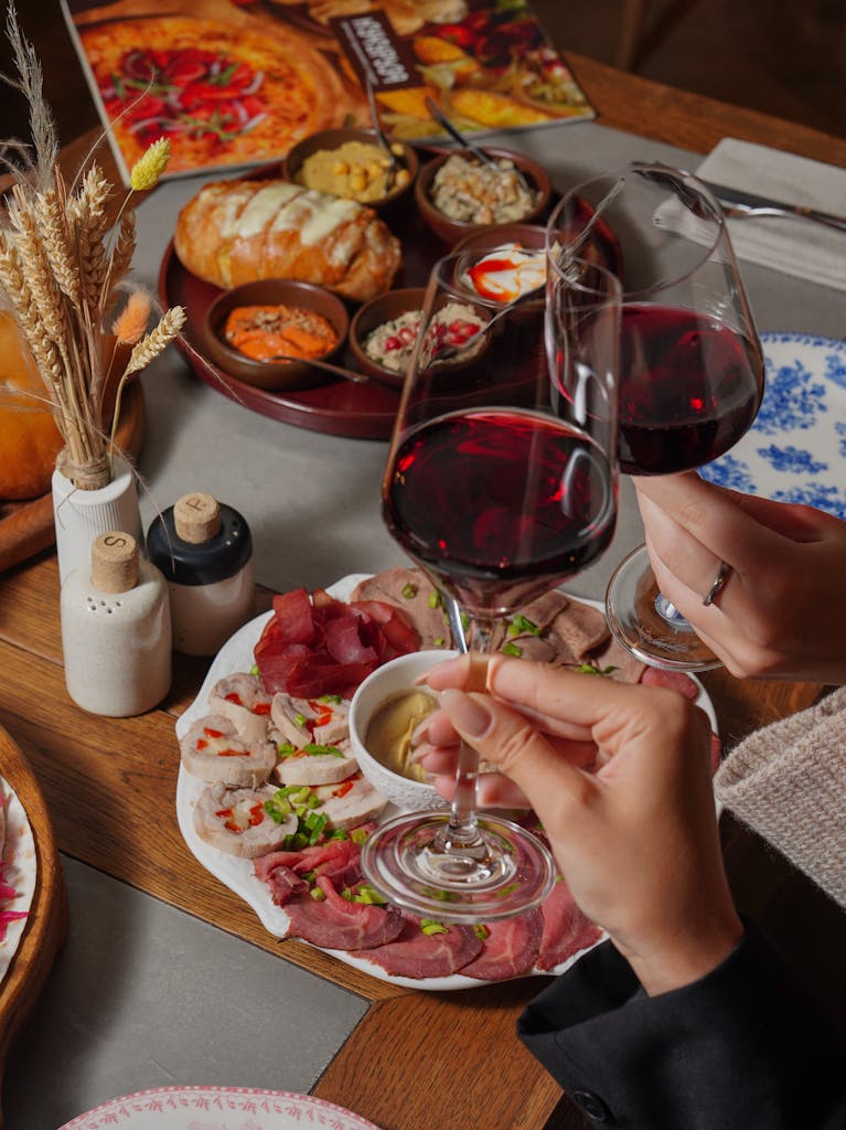 A cozy dinner setting with red wine and a variety of appetizers on a rustic wooden table.