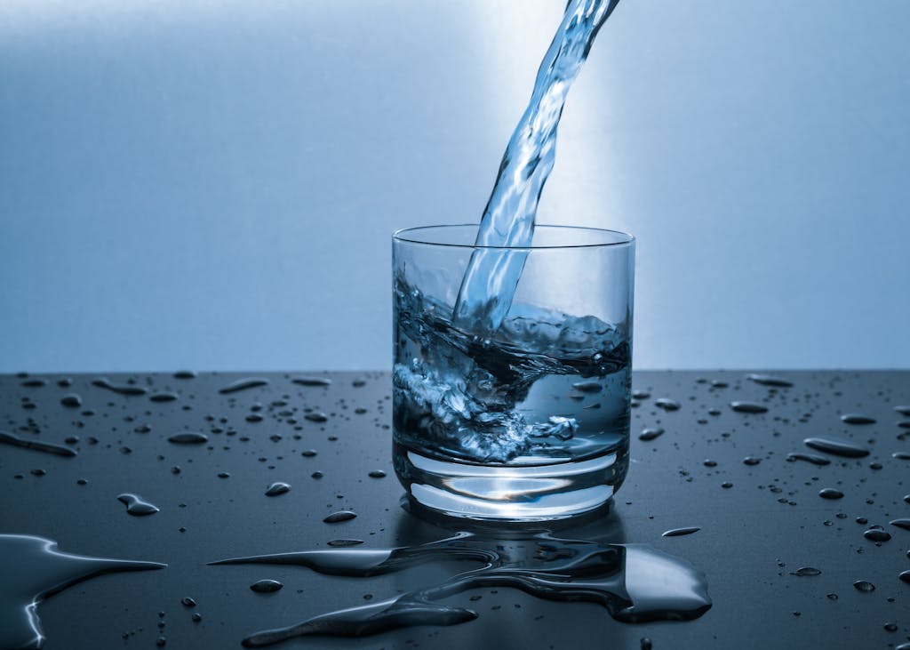 High-quality image of water being poured from a non-toxic water filter into a glass, illustrating hydration and purity.