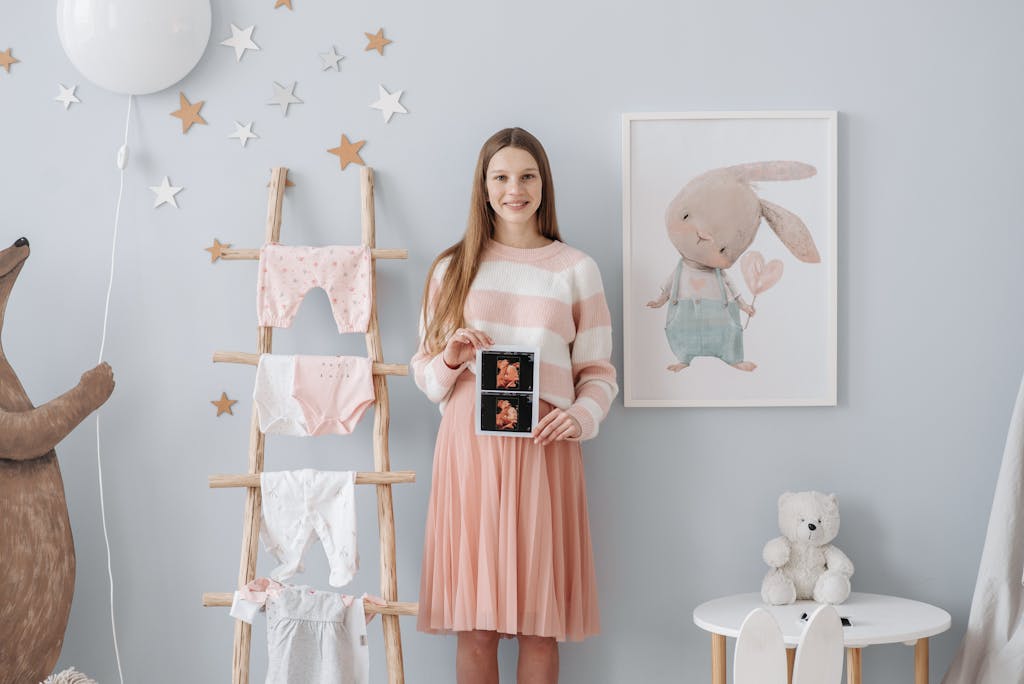 Smiling pregnant woman poses with ultrasound in a beautifully decorated nursery.