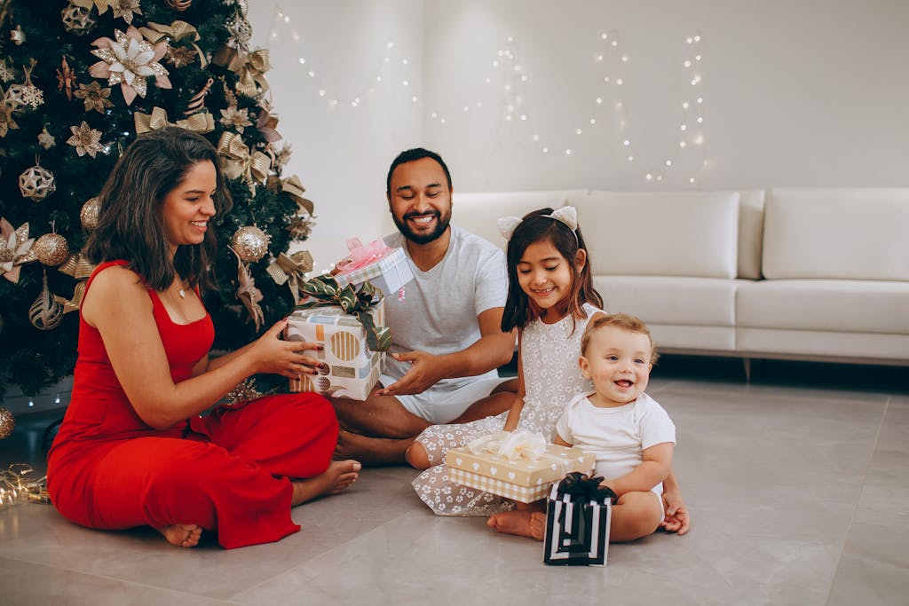 Happy family opening non-toxic Christmas gifts by the decorated tree indoors.