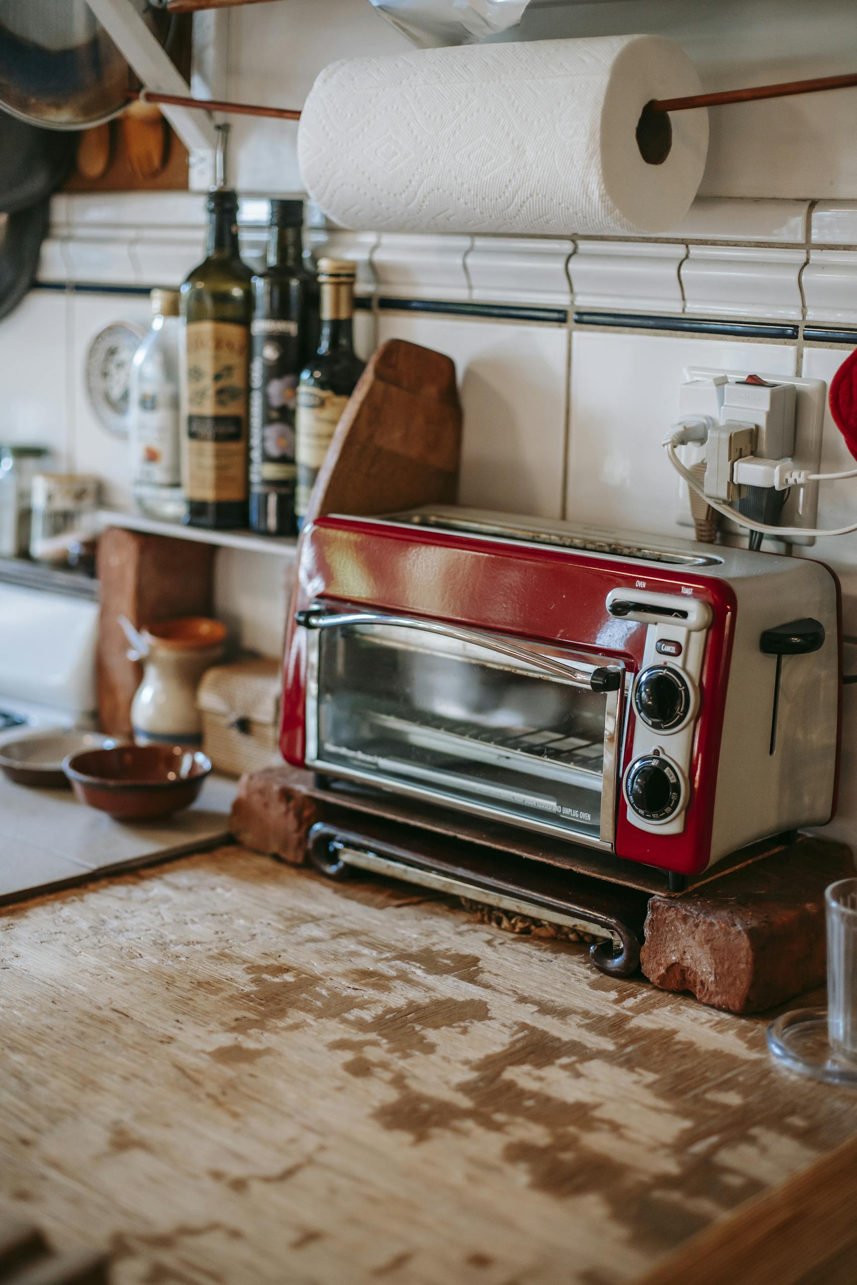 Part of kitchen with paper towels and toaster oven standing on old shabby table
