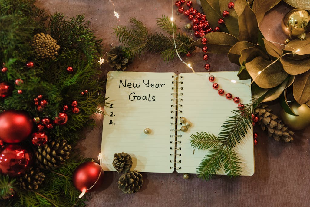 Spiral notebook with New Year goals amidst holiday decorations and Christmas ornaments.