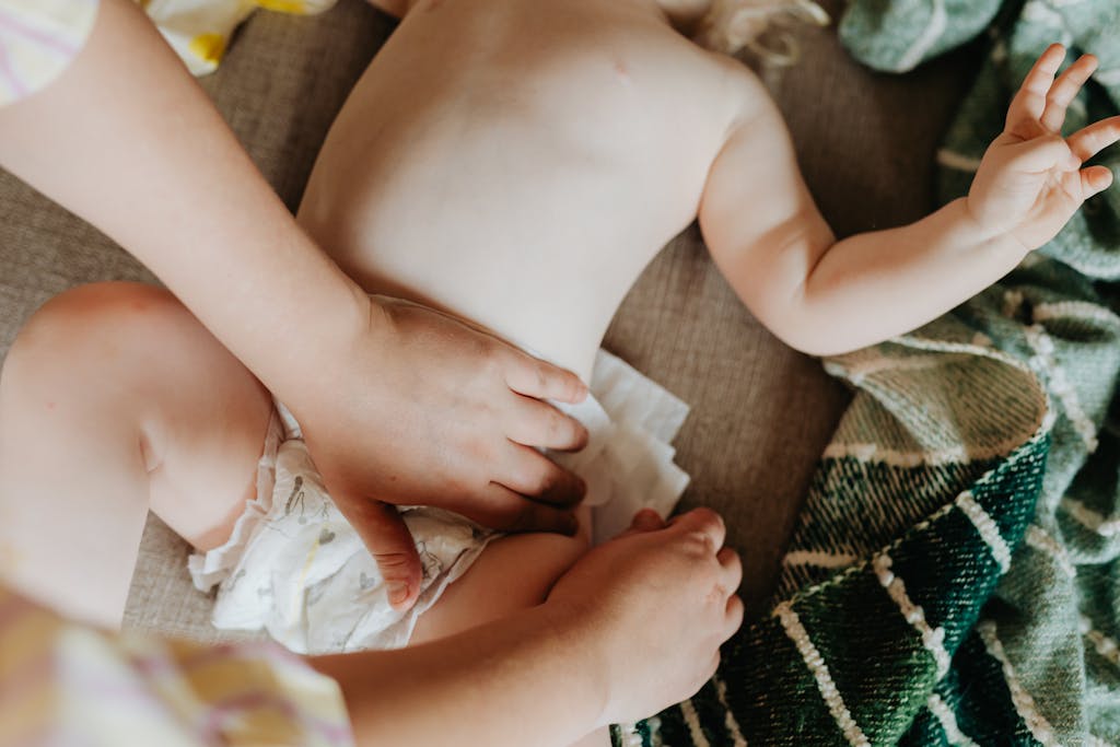 A parent changing a baby's non-toxic diaper indoors, showcasing nurturing care and parenting.