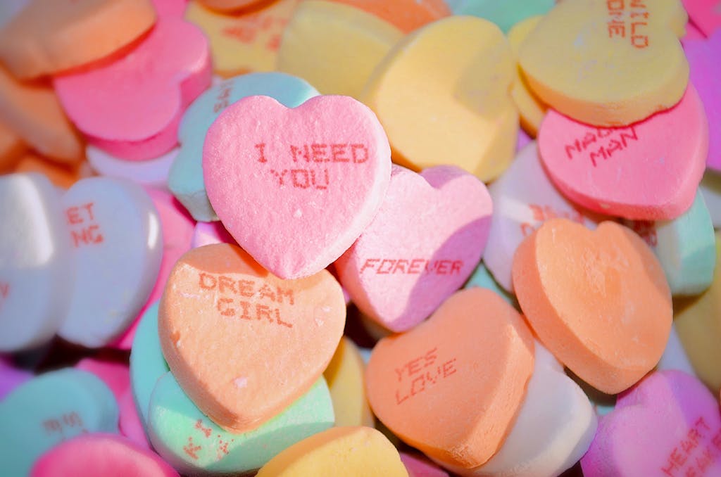 A pile of colorful heart-shaped candies with romantic messages, ideal for Valentine's Day.