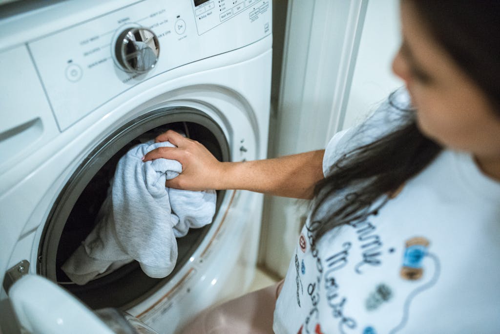 A woman loading laundry into a washing machine indoors, focusing on household chores.
