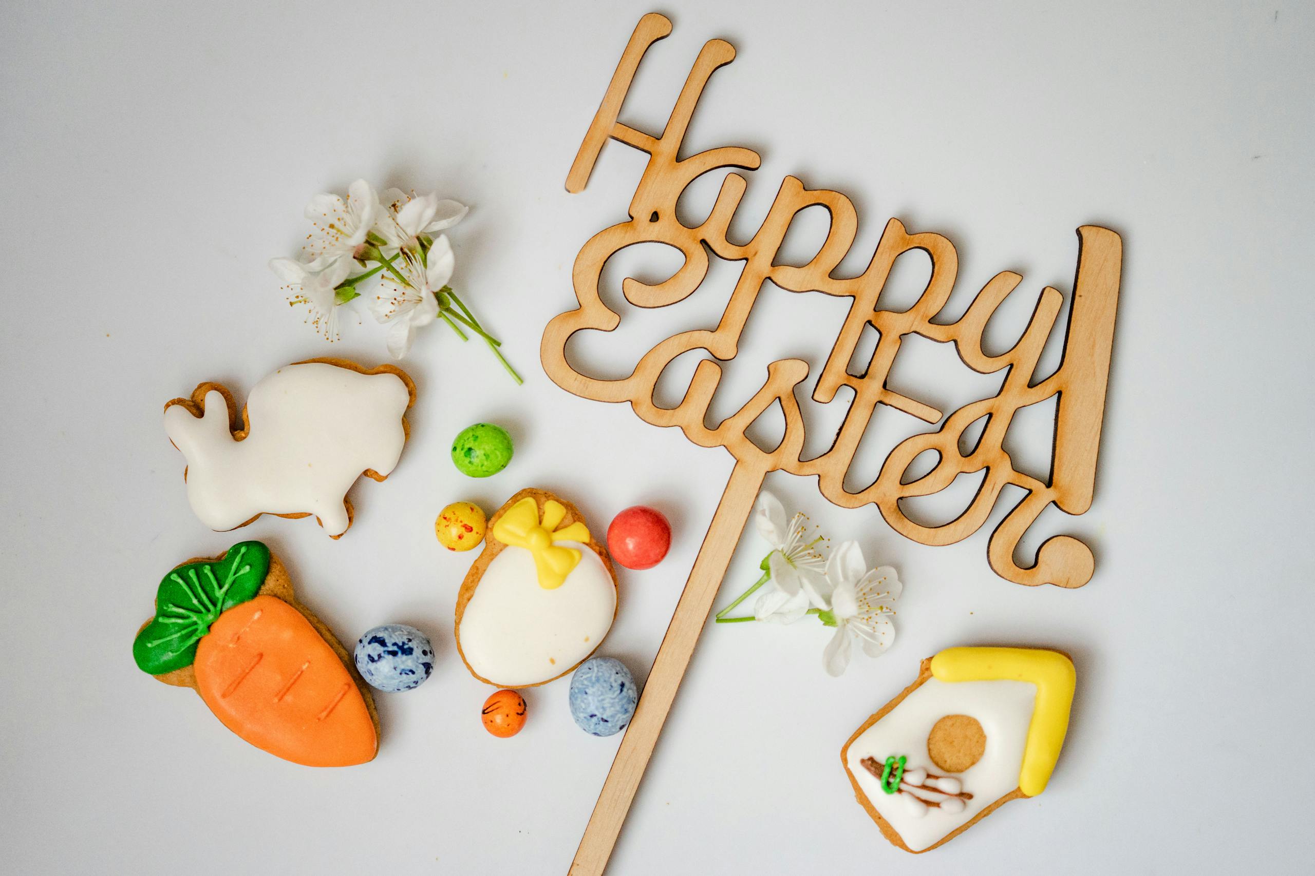 A top view of Easter cookies, decorations, and the text 'Happy Easter' on a white background.