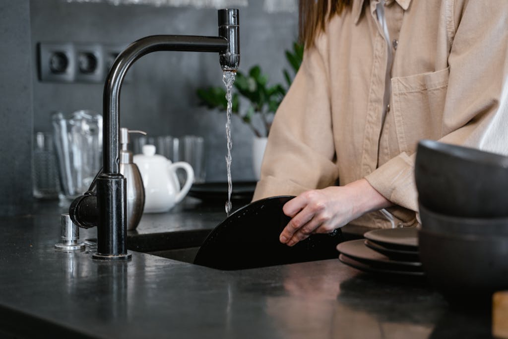 Close-up of a person washing dishes with non-toxic dish soap