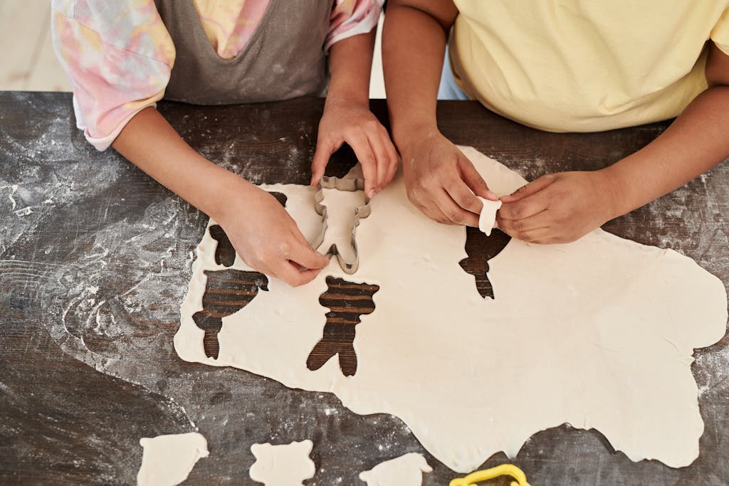 Kids cutting dough into bunny shapes for baking with fun and creativity.