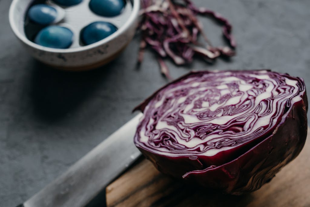 A close-up of vibrant blue Easter eggs dyed with red cabbage on a textured surface.