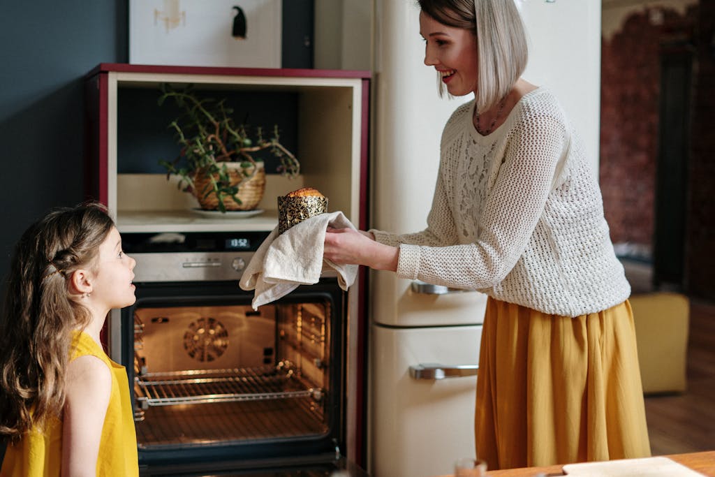 A mother and daughter enjoy bonding time while baking together in their kitchen.