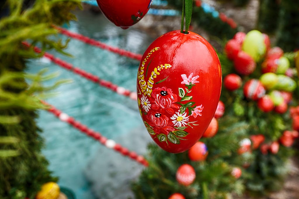 Brightly colored hand-painted Easter egg hanging outdoors among greenery, celebrating seasonal decoration.