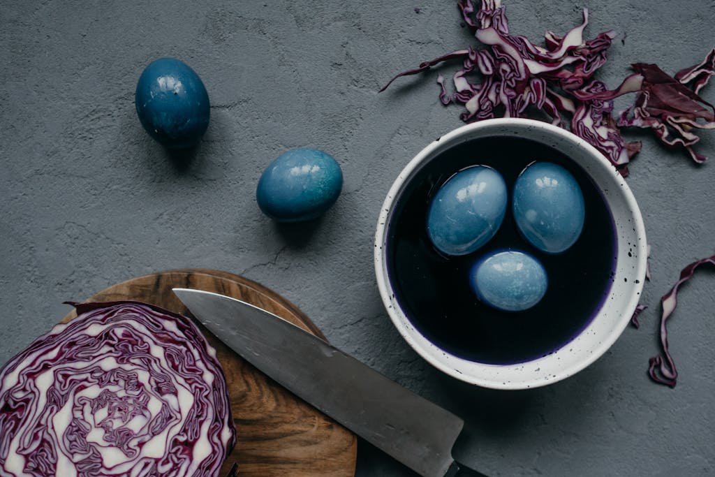 Flat lay of blue Easter eggs dyed with red cabbage on a textured concrete background.