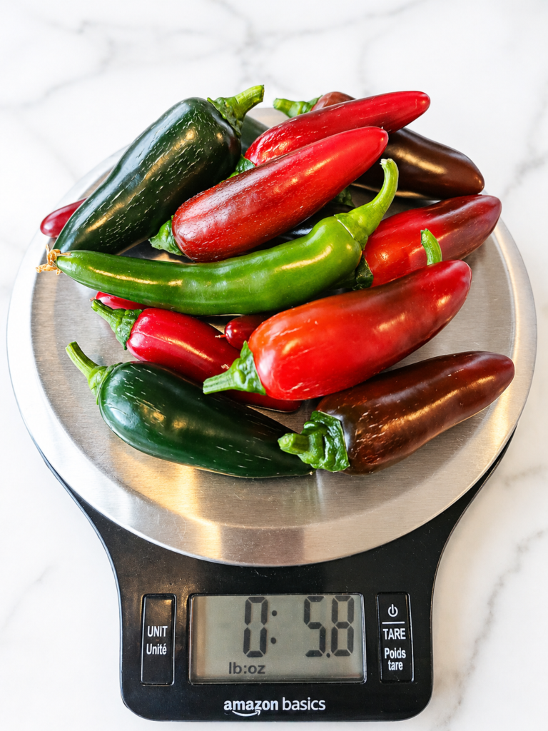 assorted peppers harvested from an indoor smart garden sit on a kitchen scale showing over 5 ounces 