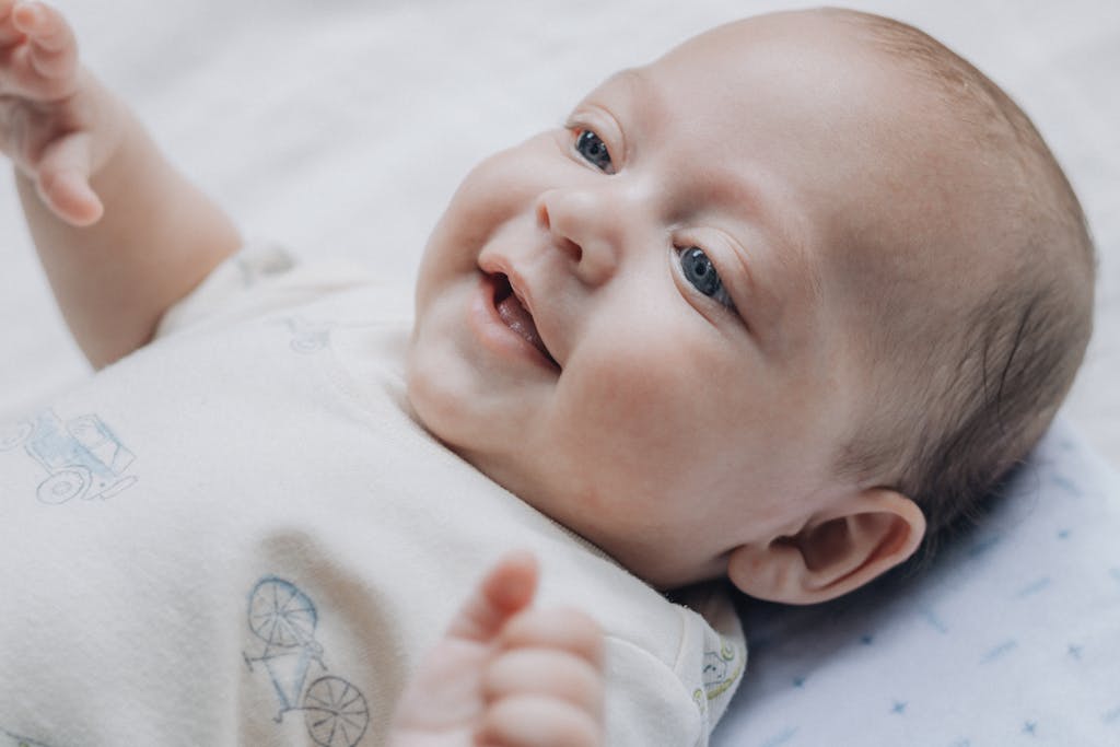 Adorable baby smiling and lying on a soft blanket, expressing happiness and warmth.