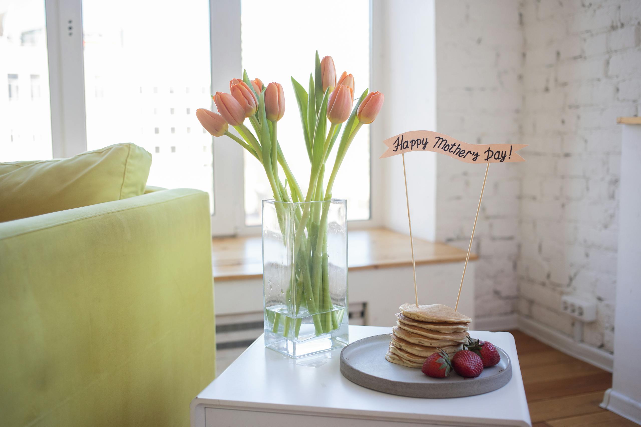 Bright and cozy Mother's Day setup with pancakes and tulips indoors.