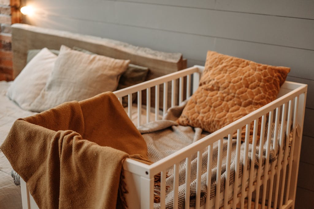 A cozy bedroom featuring a white crib with warm blankets and pillows, creating a comfortable ambiance.