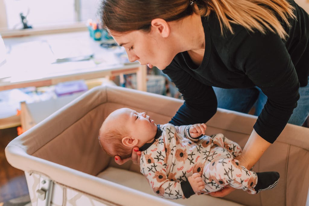 A mother lovingly interacts with her baby in a cozy non-toxic bassinet setting, emphasizing parental affection.
