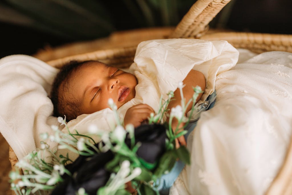 A serene newborn baby sleeping in a wicker bassinet with delicate flowers.