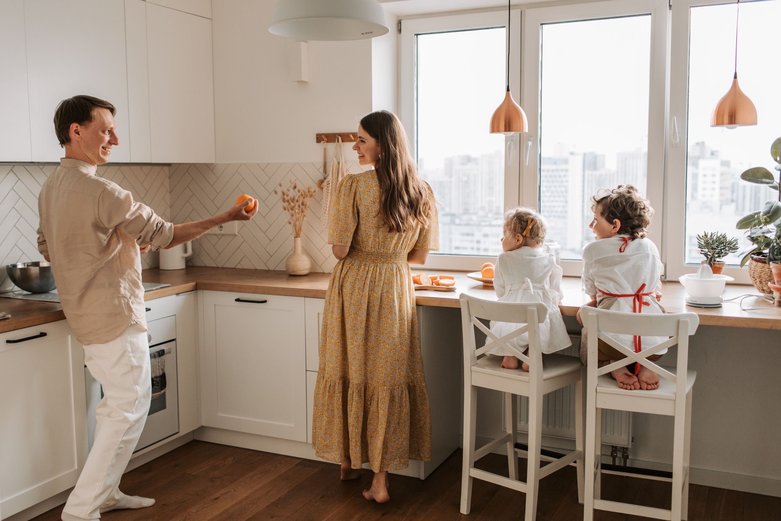A family having fun preparing breakfast in a cozy kitchen with a city view.