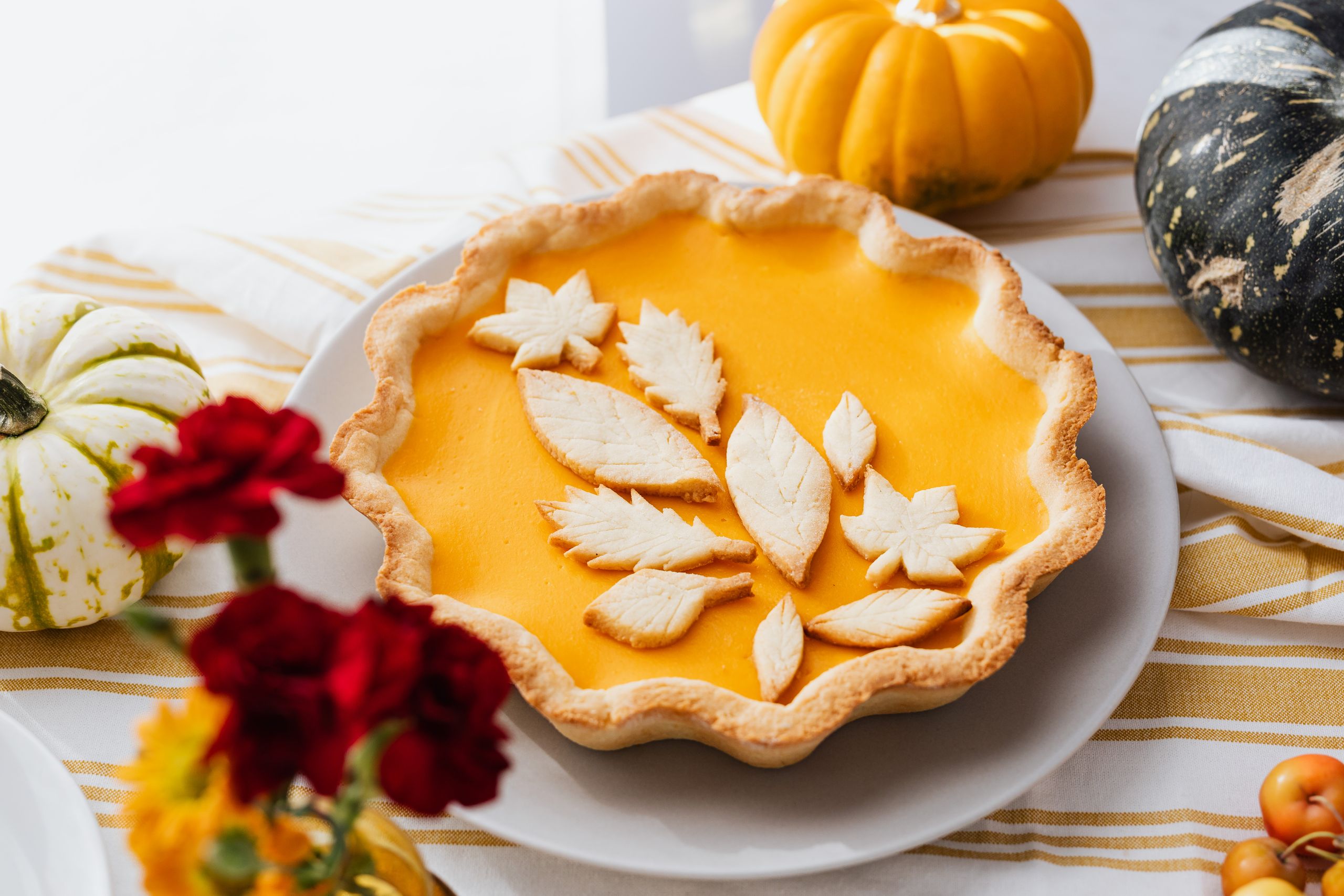 Close-up of a beautifully decorated pumpkin pie with autumn leaf cutouts, perfect for fall celebrations.