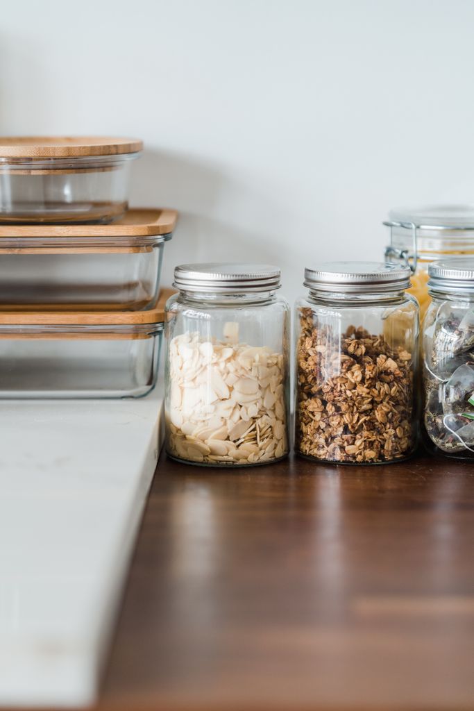 Neat kitchen setup with glass jars filled with snacks and food storage containers on a wooden counter.