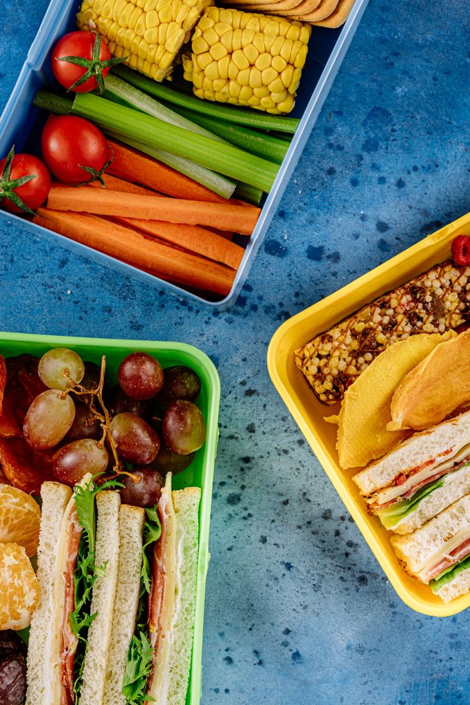 A vibrant flat lay of healthy lunch boxes featuring sandwiches, fruits, and vegetables, perfect for a nutritious meal.